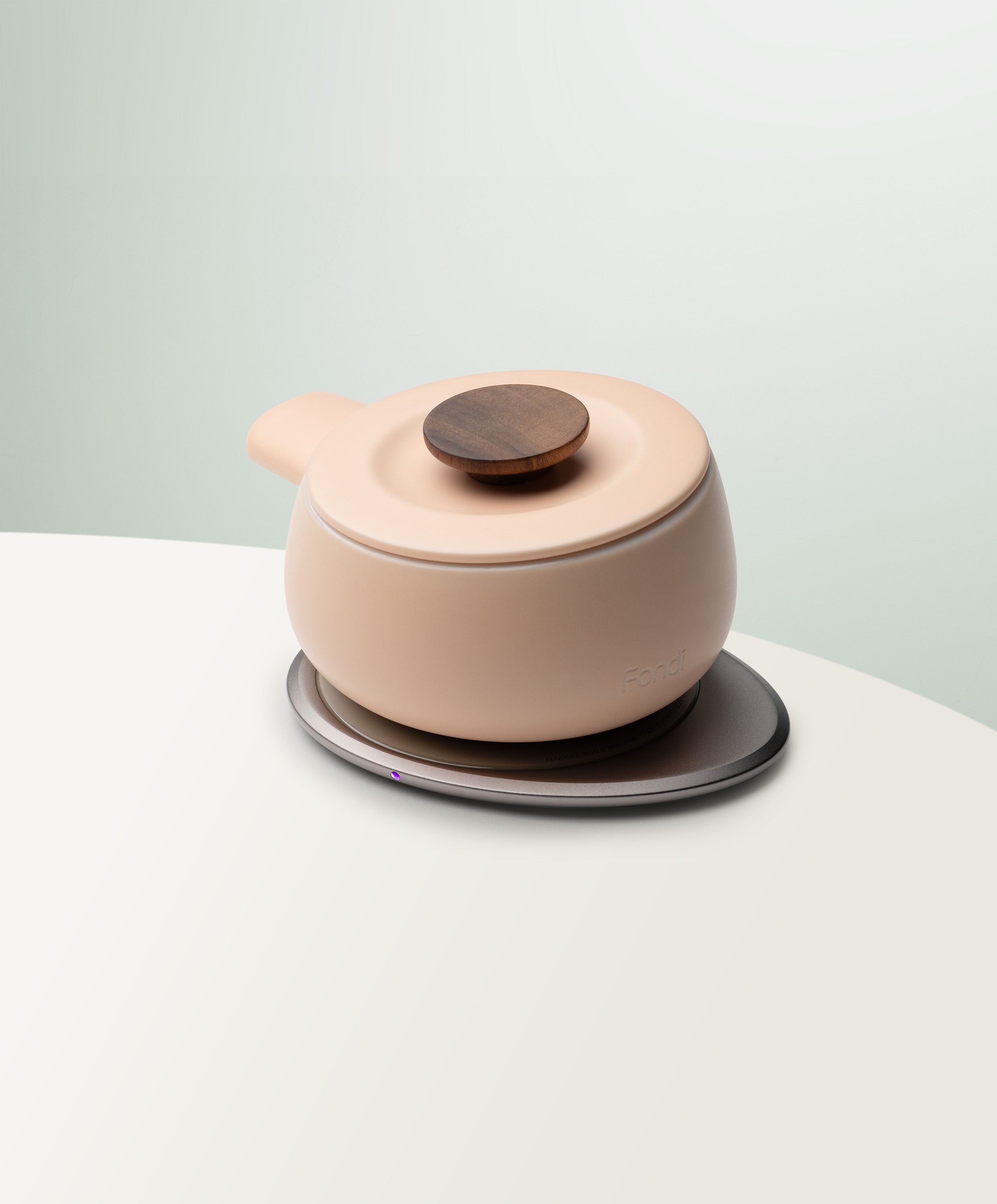 Fondi Self-Heating Ceramic Fondue 7.6 fl oz / 225 mL in Rosy Apricot angled top-side view on OHOM Charging Pad 3
