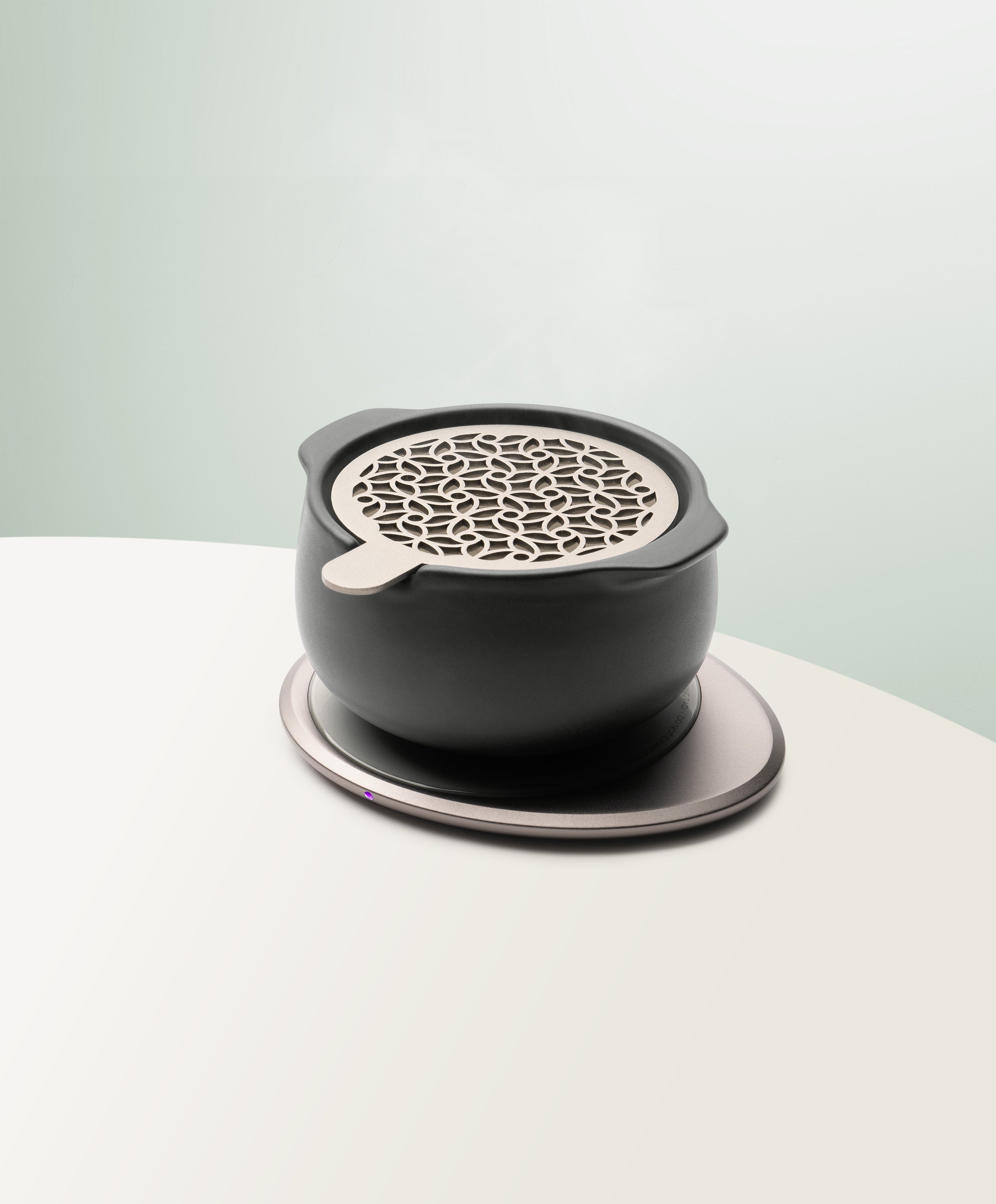 Jun Self-Heating Ceramic Diffuser 5 fl oz / 150 mL with lid in Inkstone Black angled view on Ohom Pad 3