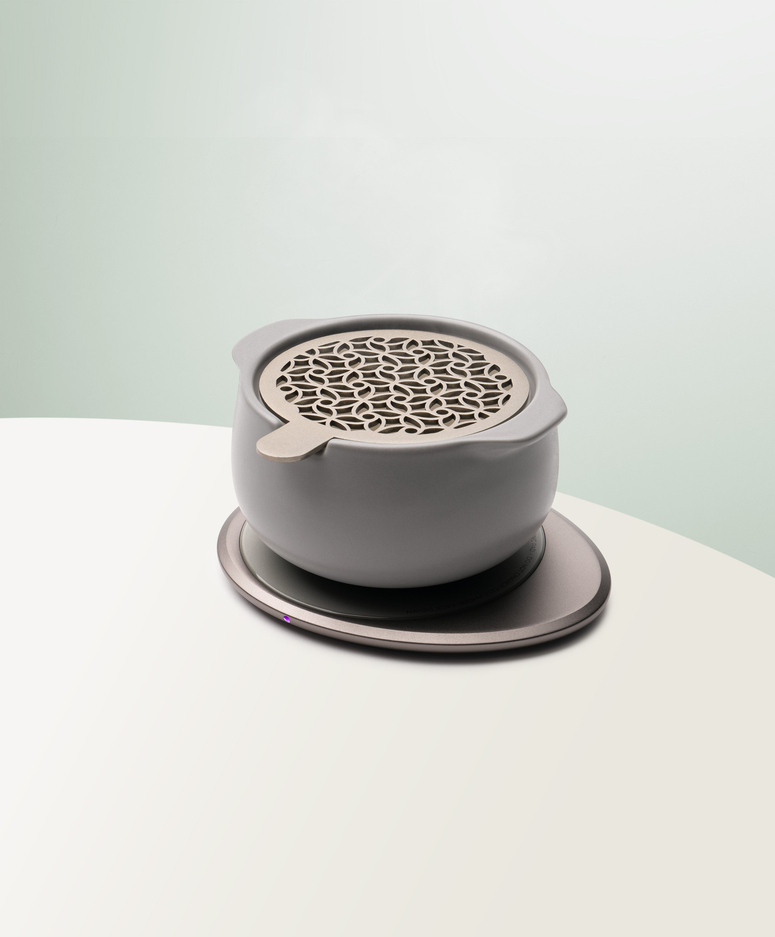 Jun Self-Heating Ceramic Diffuser 5 fl oz / 150 mL with lid in Soft Gray angled view on Ohom Pad 3