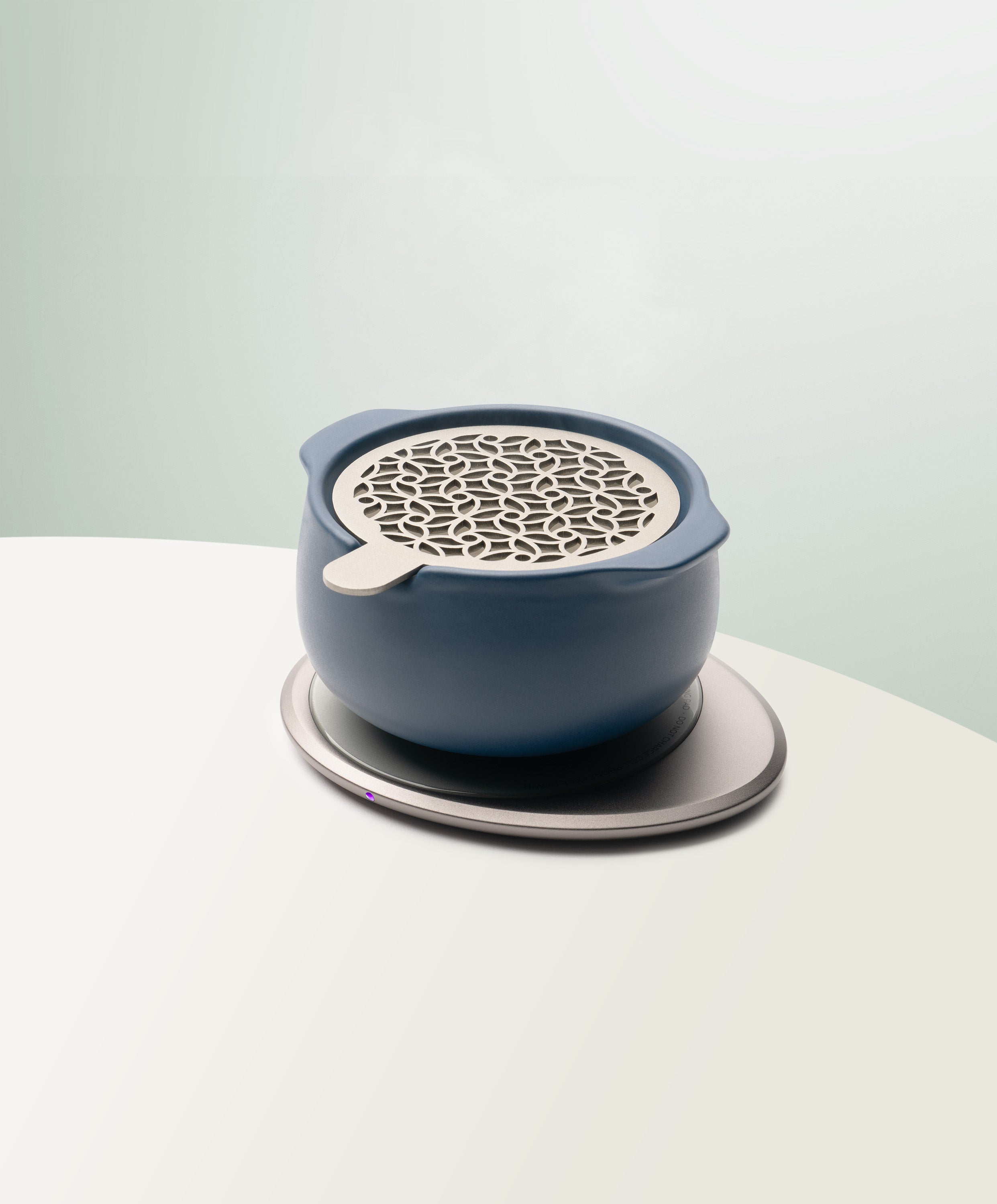 Jun Self-Heating Ceramic Diffuser 5 fl oz / 150 mL with lid in Deep Navy angled view on Ohom Pad 3