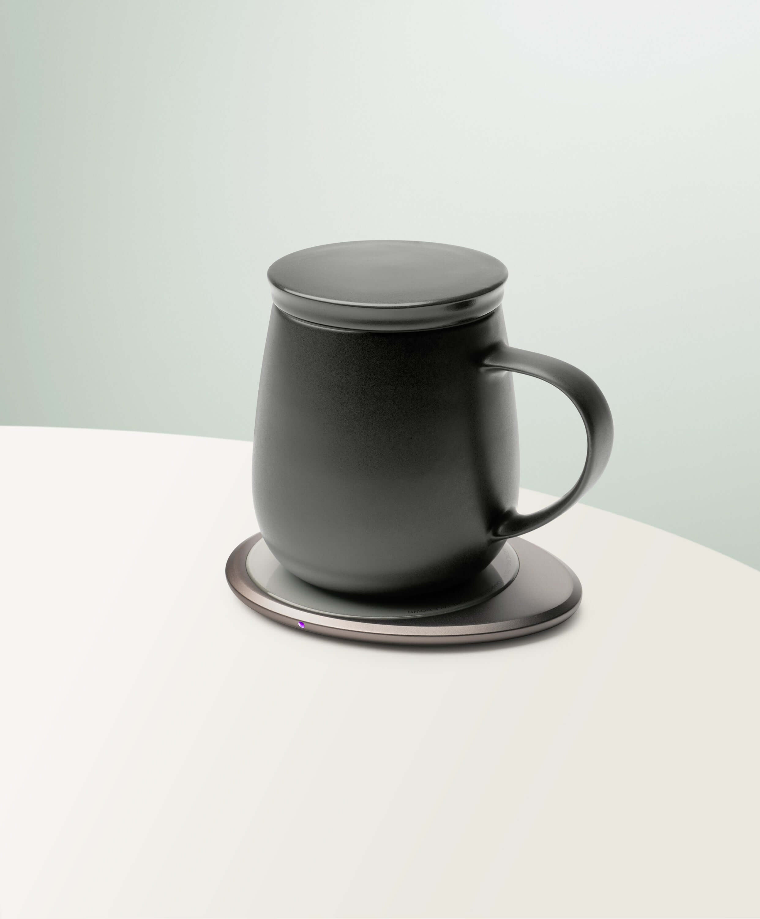 Ui 3 Self-Heating Ceramic Mug 12 fl oz / 355 mL in Inkstone Black with lid angled top-side view on OHOM Charging Pad 3