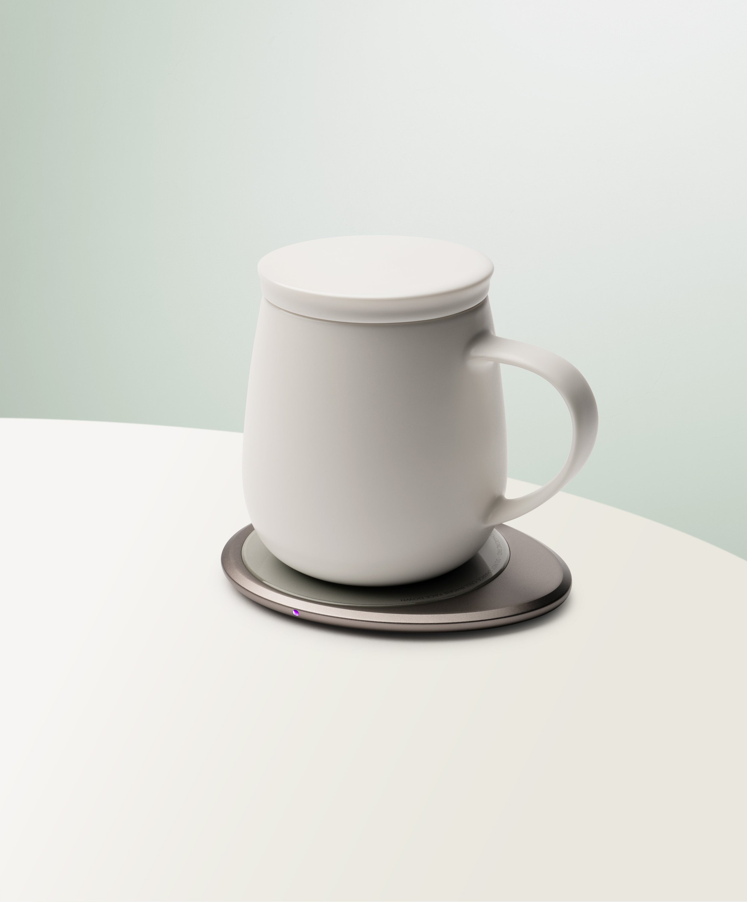 Ui 3 Self-Heating Ceramic Mug 12 fl oz / 355 mL in Jasmine White with lid angled top-side view on OHOM Charging Pad 3
