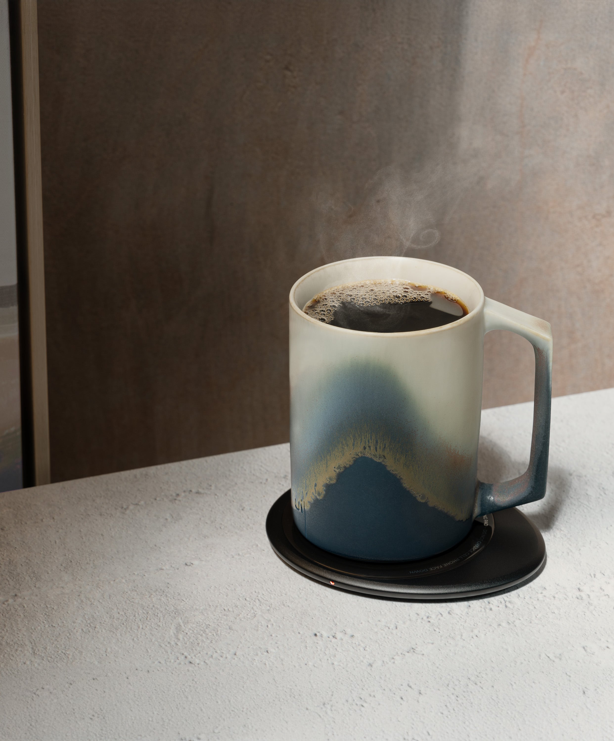 Ui Artist Collection Self-Heating Ceramic Mug 12 fl oz / 355 mL in Arctic Radiance with lid angled top-side view on Ohom Charging Pad 3