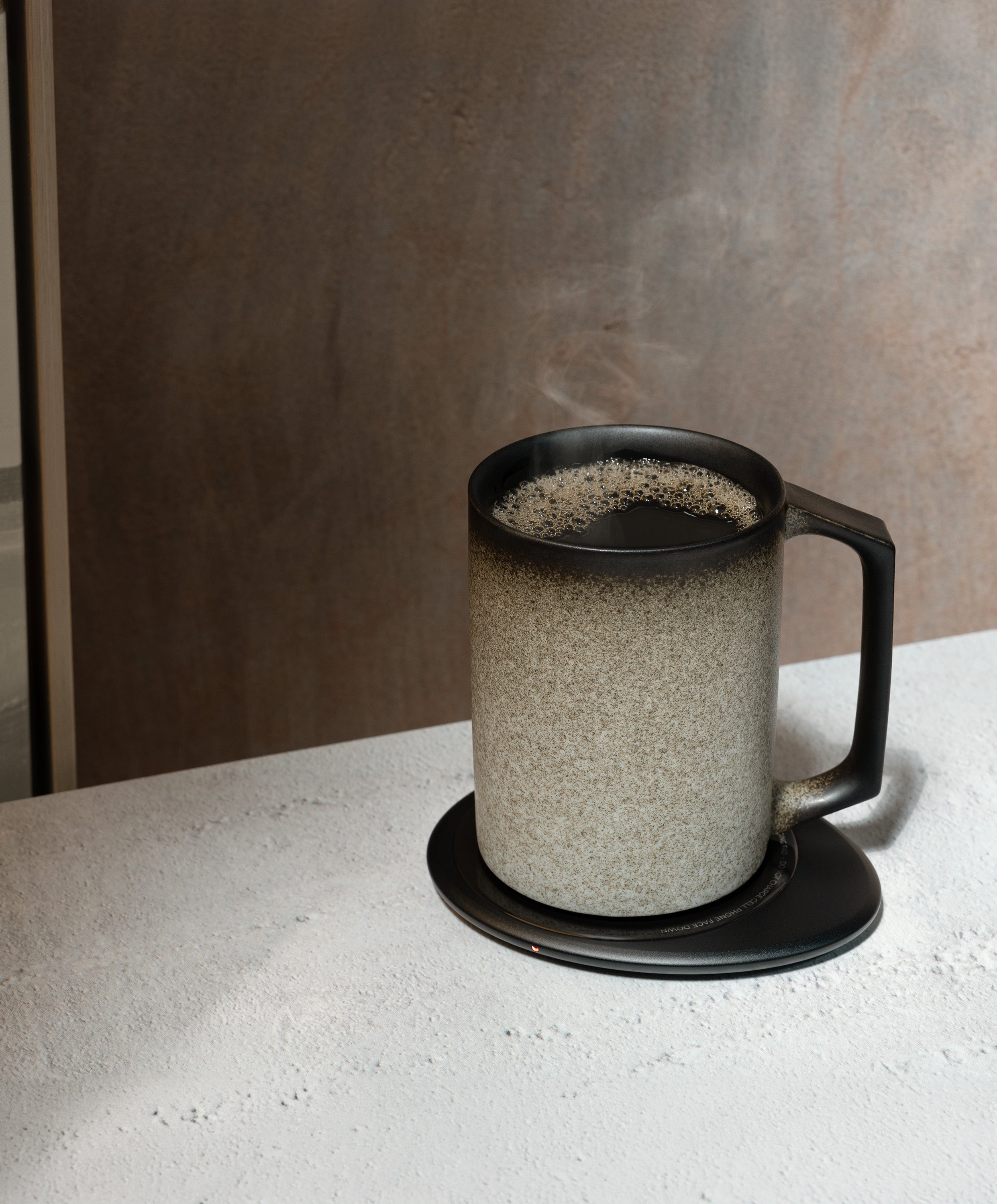 Ui Artist Collection Self-Heating Ceramic Mug 12 fl oz / 355 mL in Iron Noir angled top-side view on OHOM Charging Pad 3
