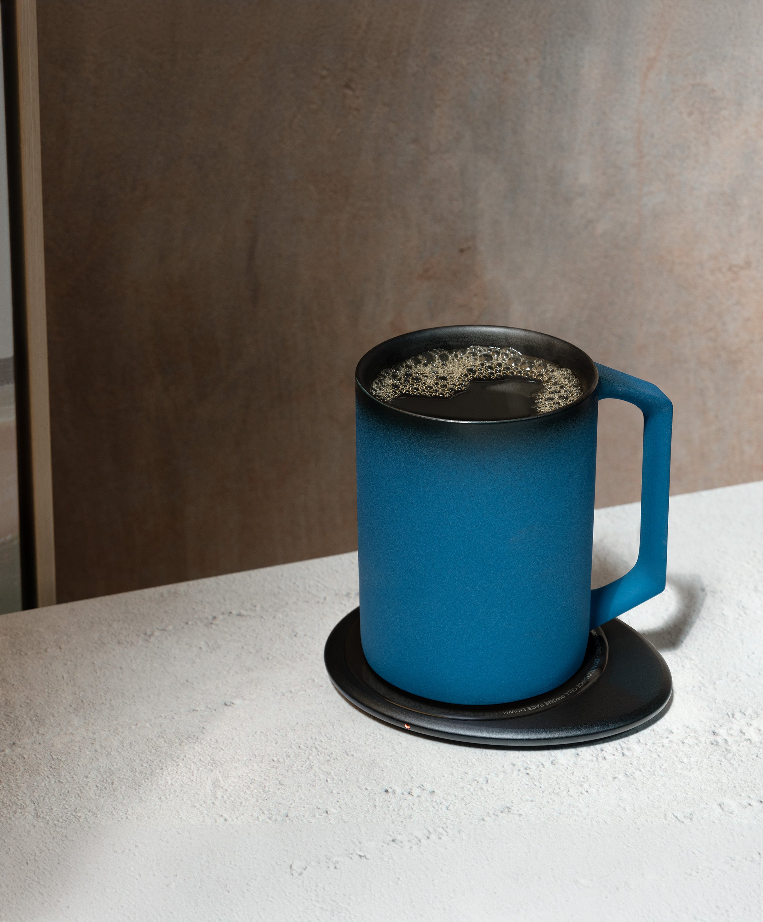 Ui Artist Collection Self-Heating Ceramic Mug 12 fl oz / 355 mL in Midnight Abyss with lid angled top-side view on Ohom Charging Pad 3