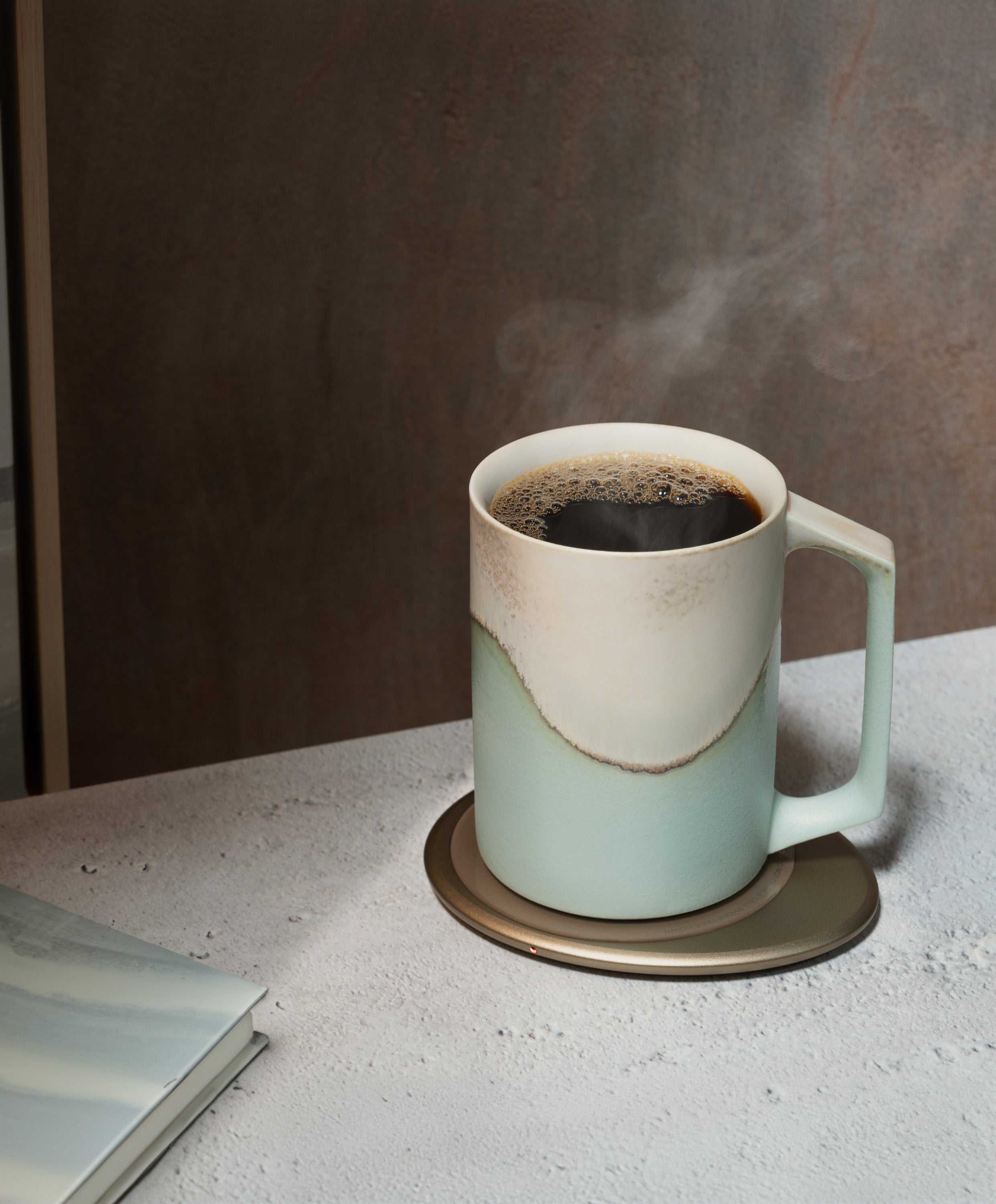 Ui Artist Collection Self-Heating Ceramic Mug 12 fl oz / 355 mL in Mint Glacier with lid angled top-side view on Ohom Charging Pad 3