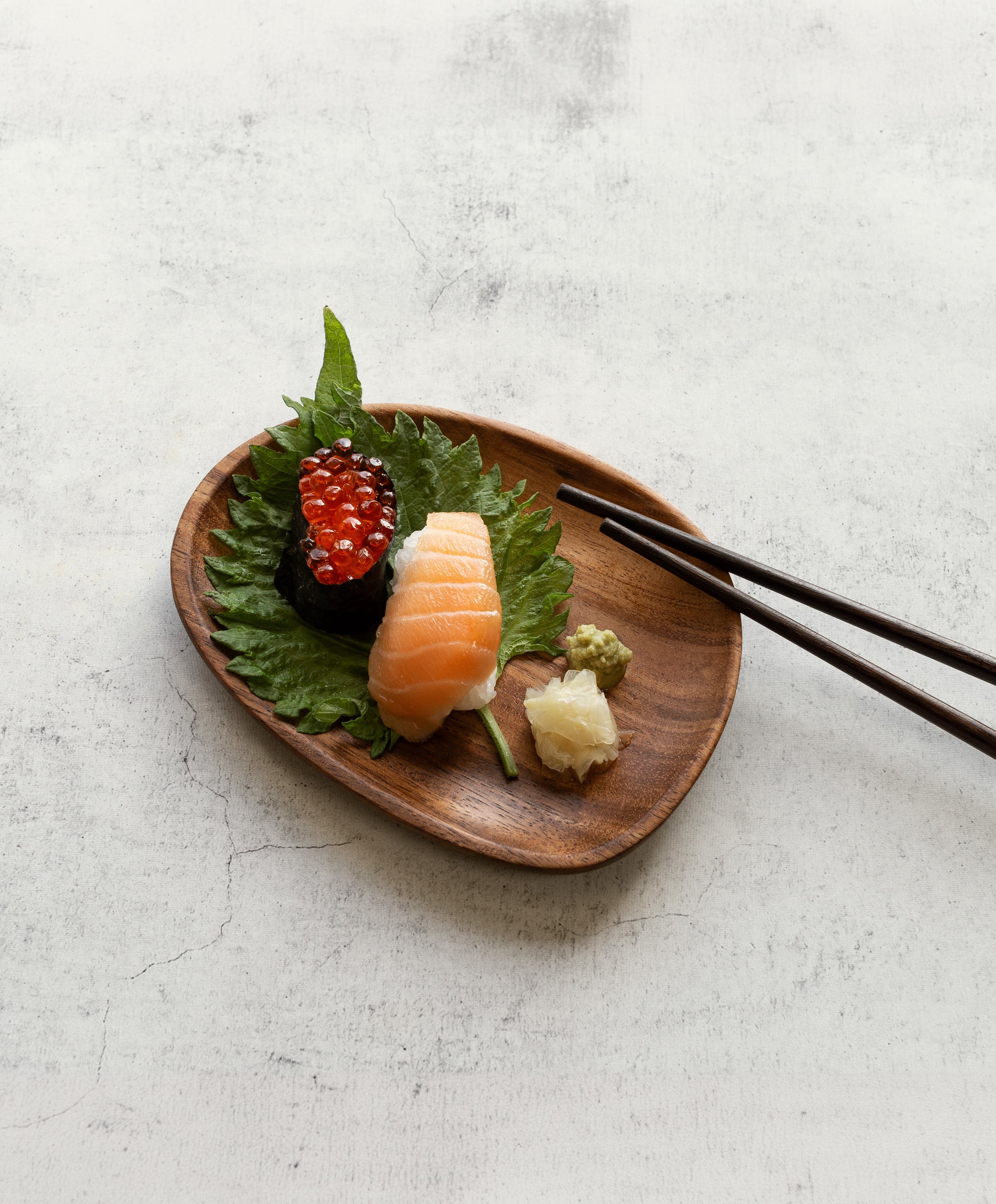 Foree wooden dinnerware set handcrafted from solid Acacia wood with medium plate holding sushi, OHOM chopsticks about to pick up sushi