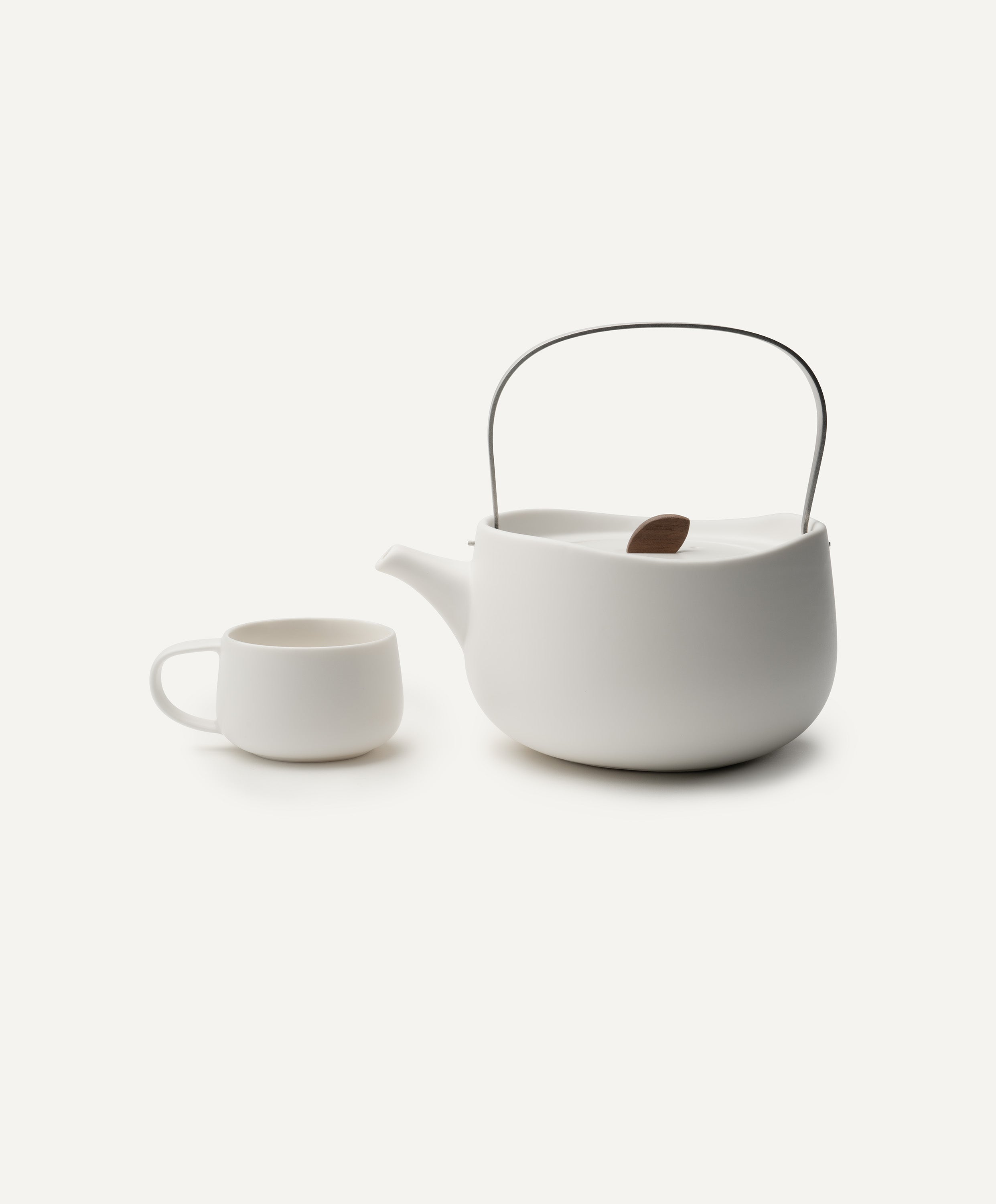 Leiph self-heating ceramic teapot 20 fl oz / 600 mL in Jasmine White with lid on top and matching teacups next to it