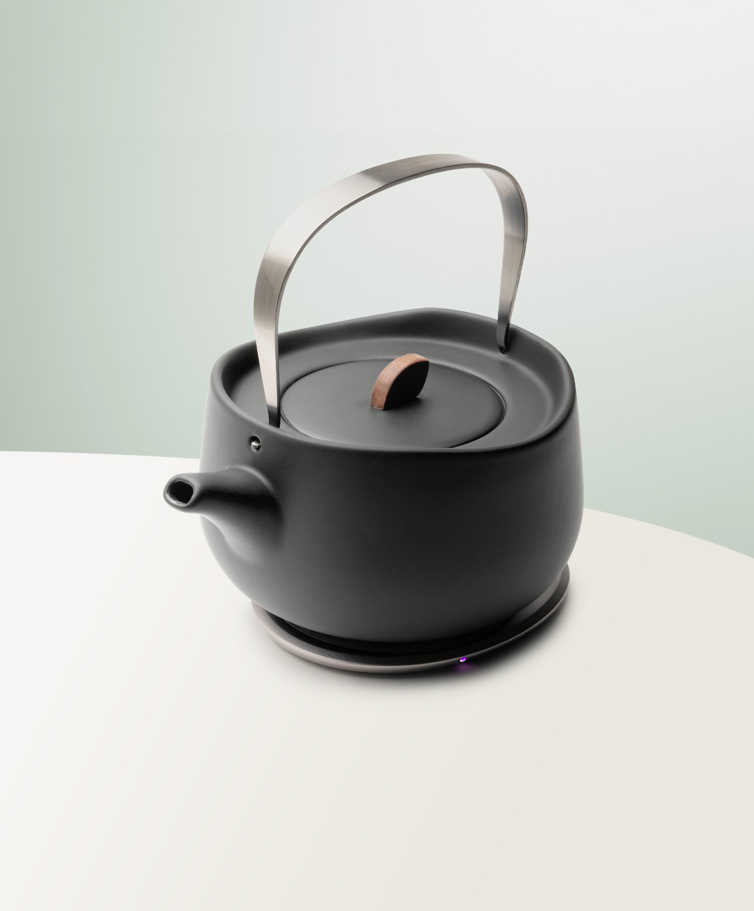 Leiph Self-Heating Ceramic Teapot Set 20 fl oz / 600 mL in Inkstone Black angled top-side view on OHOM Charging Pad 3