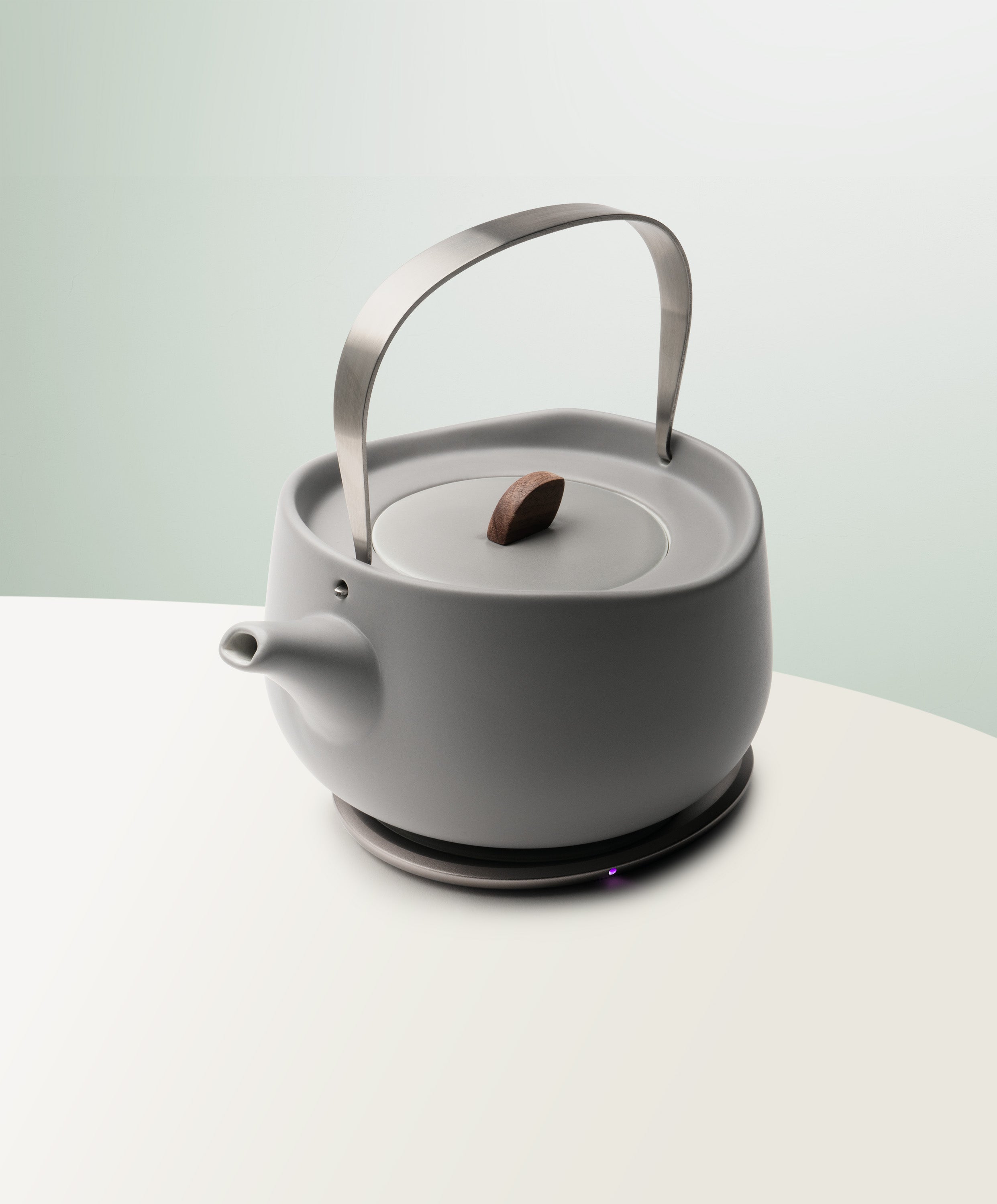 Leiph Self-Heating Ceramic Teapot Set 20 fl oz / 600 mL in Soft Gray angled top-side view on OHOM Charging Pad 3