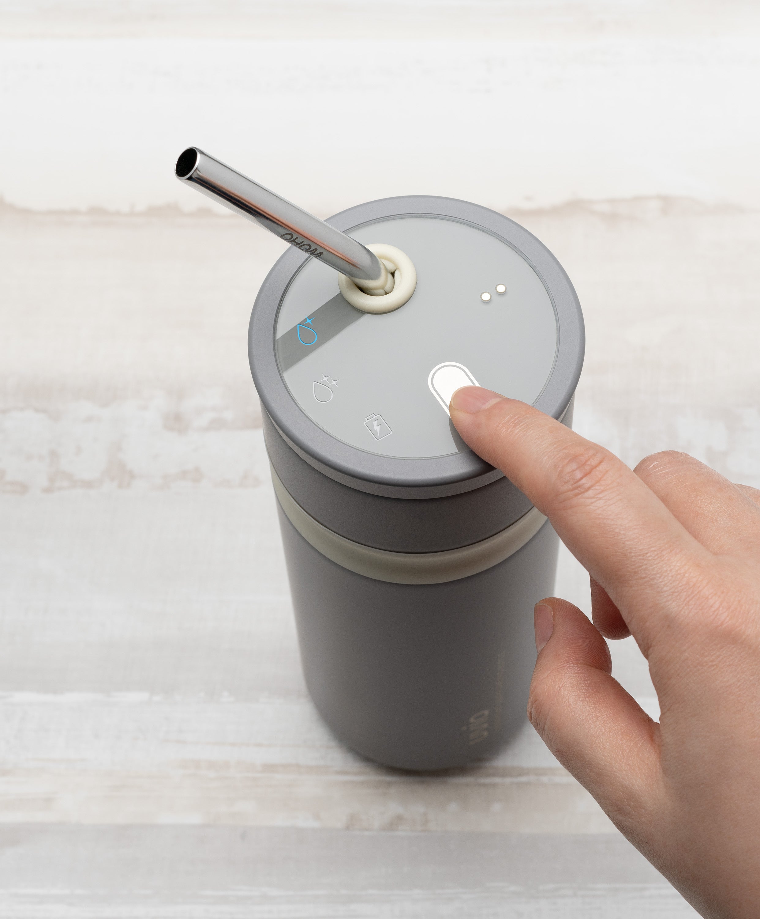 Person pressing button on Uvio self-purifying water bottle 16 fl oz / 480 mL in Elephant Gray to activate UV-C purification