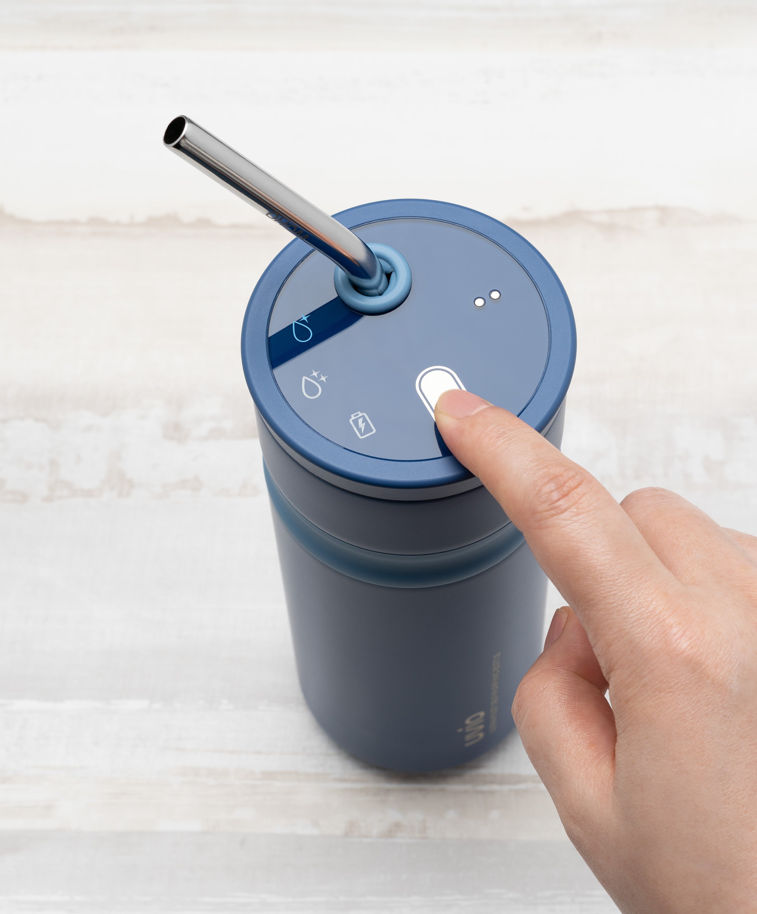 Person pressing button on Uvio self-purifying water bottle 16 fl oz / 480 mL in Picasso Blue to activate UV-C purification