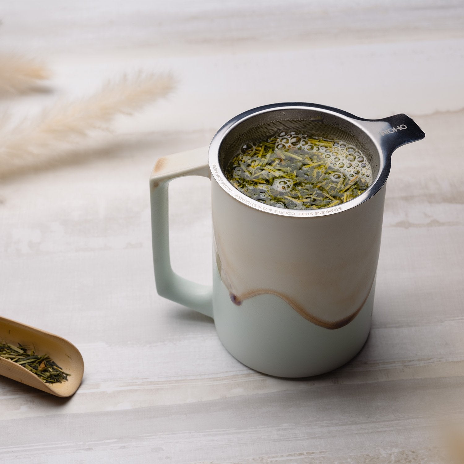Large tea strainer with mint colored mug filled with hot water