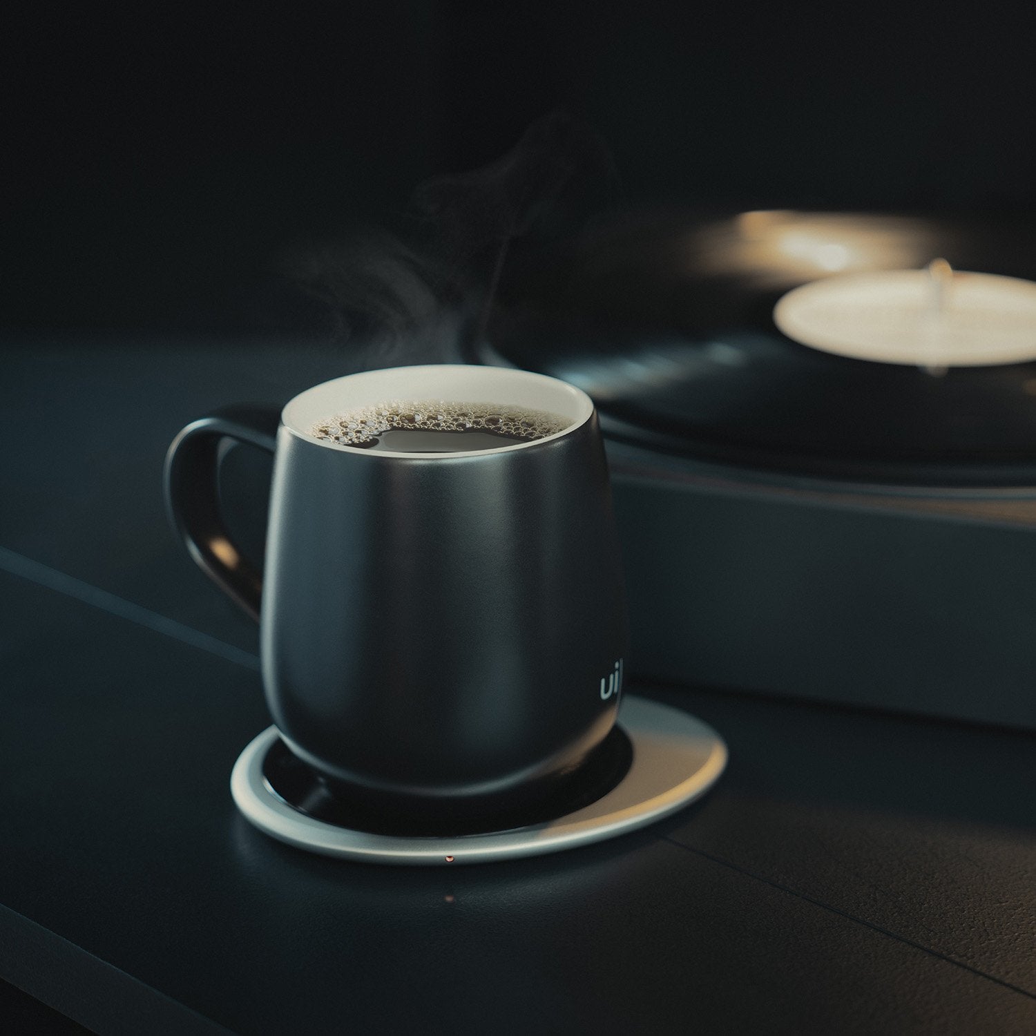Black mug with hot tea on heating pad