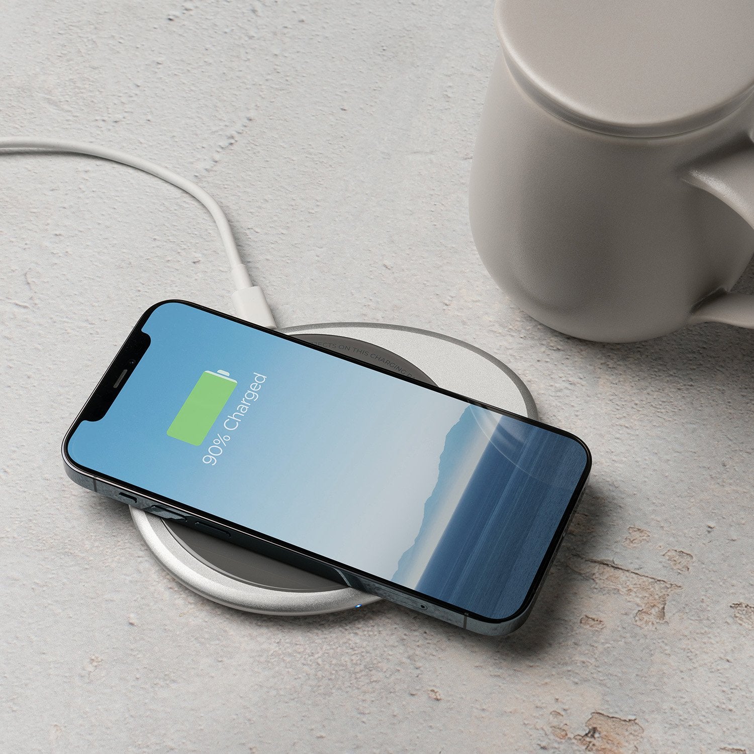 Phone on charging pad next to mug
