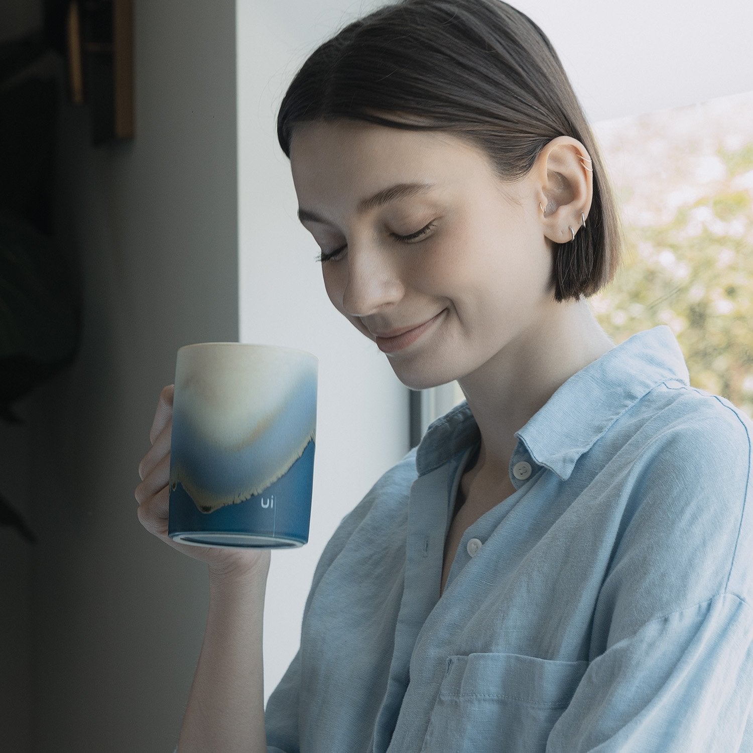 Smiling woman holding blue mug with design