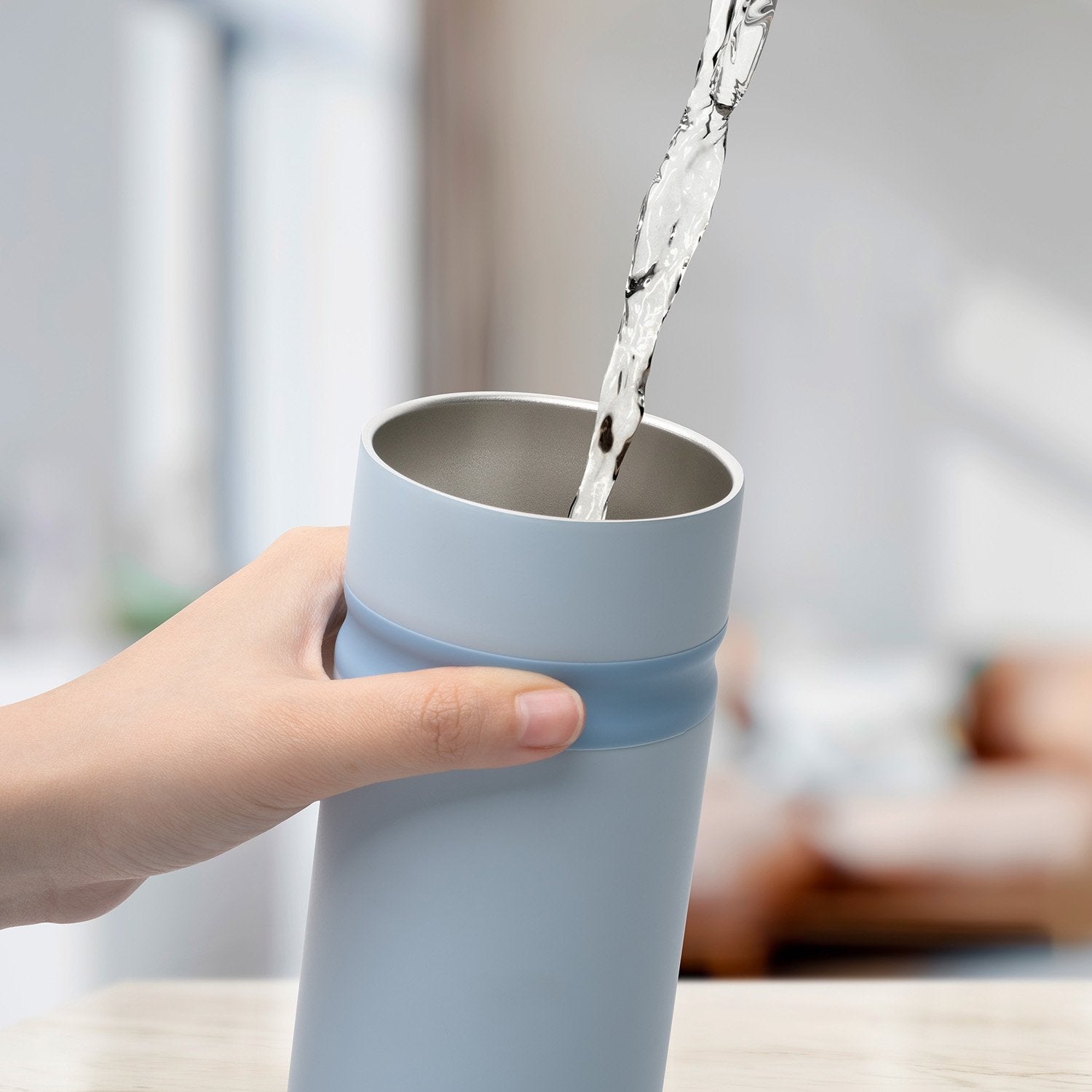 Water pouring into light blue metal bottle