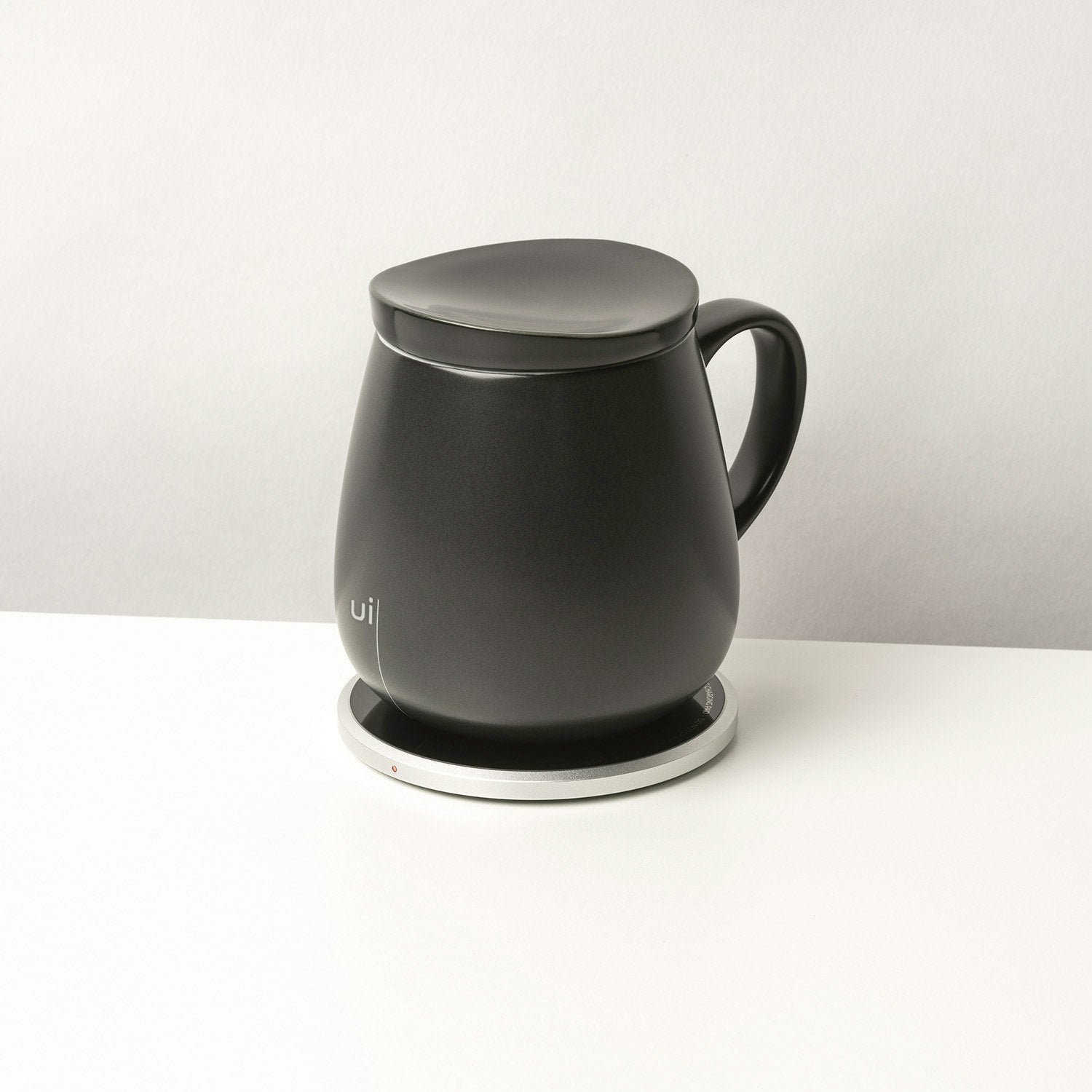 Large black mug with lid on heating pad