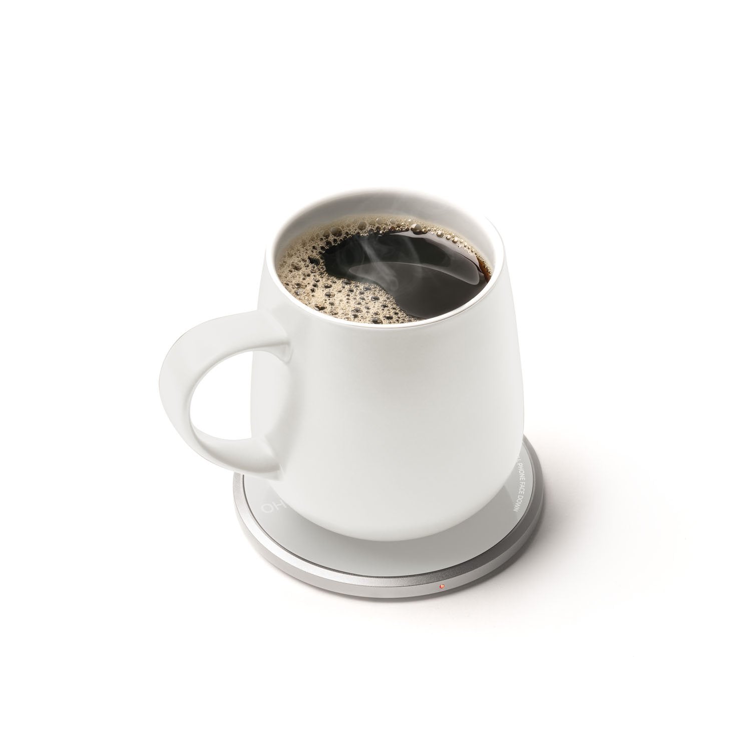 White mug with coffee on heating pad